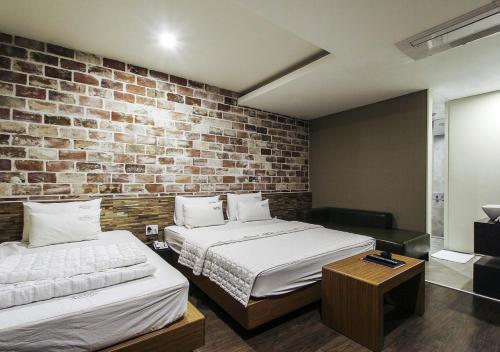 a bedroom with two beds and a brick wall at Arieti A in Gimhae