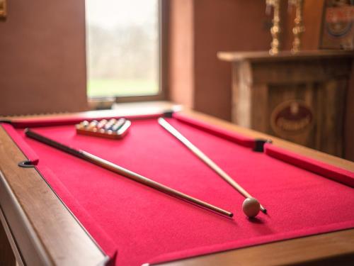 a red pool table with two cue balls and twosticks at Manhay Nature Stay, Luxembourg in Manhay
