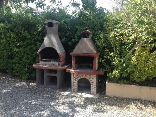 two outdoor ovens sitting next to a hedge at Garden Relais Le Fontanelle in Montescudaio