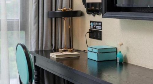 a desk with a lamp and a blue box on it at Xana Hotelle Shenzheng South Station Foxconn in Shenzhen