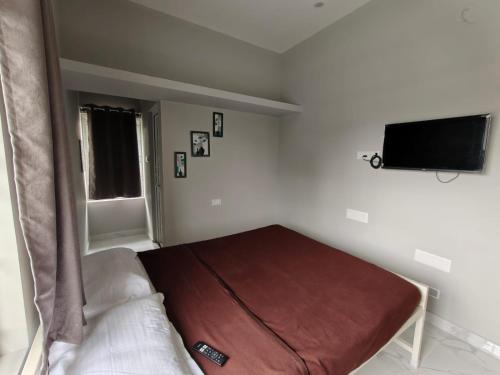 a bedroom with a bed and a flat screen tv at AVANI Stays in Yelagiri