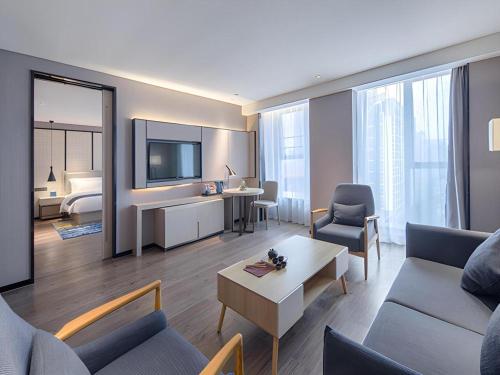 a living room with a couch and a room with a bed at Echarm Hotel Nanning the MixC Dongmeng Business District in Nanning