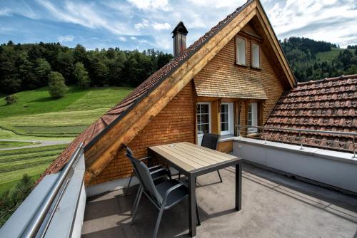 Casa pequeña con balcón con mesa y sillas. en Hof Mazenau, en Appenzell