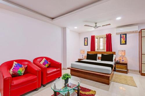 a bedroom with a bed and two red chairs at Super Townhouse Seethammadhara Junction Formerly Vijaya Residency in Raspari Palao