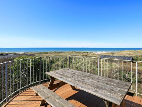 a wooden bench sitting on a deck with the beach at 12 person holiday home in Hirtshals-By Traum in Hirtshals