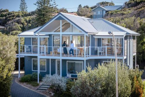 a blue house with people standing on the deck at Jay's Beach House I Private Properties in Augusta