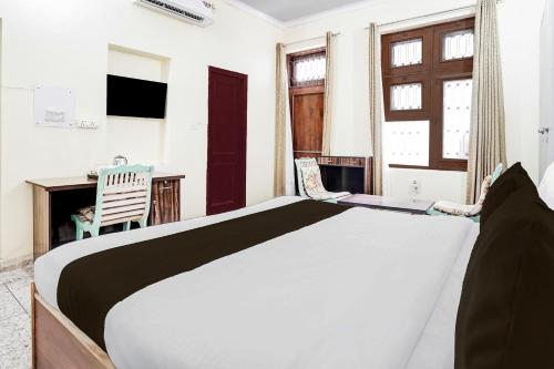a bedroom with a bed and a desk and a window at Super Hotel O Sector 21 Faridabad in Faridabad