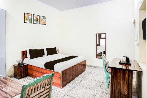 a bedroom with a bed and a table and a desk at Super Hotel O Sector 21 Faridabad in Faridabad