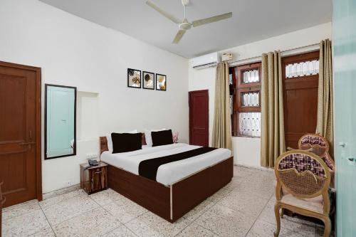 a bedroom with a bed and a chair and a window at Super Hotel O Sector 21 Faridabad in Faridabad