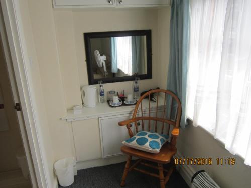 a bathroom with a chair and a mirror and a mirror at Queen Mary Inn in Poole