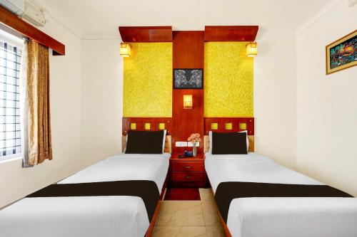 two beds in a room with white walls at Super Collection O Viyyur Thrissur in Trichūr