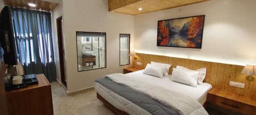 a bedroom with a bed and a painting on the wall at Hotel Premjees Paradise in Solan