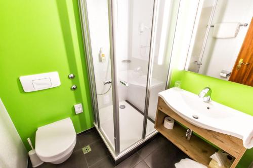 a green bathroom with a toilet and a sink at Akzent Hotel Restaurant Hirsch in Heidenheim