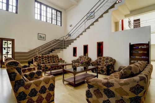 a living room with couches and a table and stairs at Super Collection O Kangarappady Formerly Cochin Residency in Kakkanad