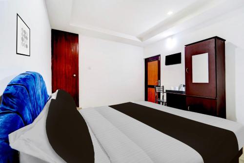 a bedroom with a bed and a blue couch at Super Hotel O Kunnamangalam Near Bus Stand in Calicut