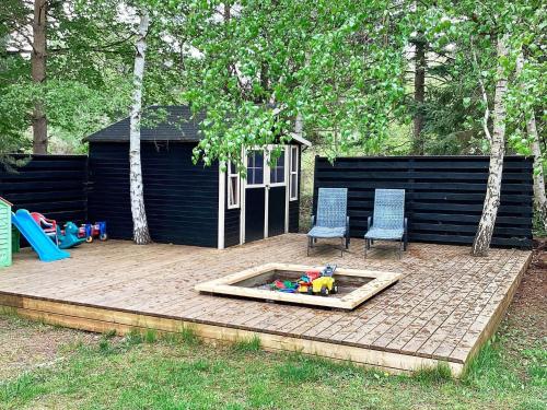 a backyard with a sandbox and two chairs and a play house at 5 star holiday home in Væggerløse in Bøtø By