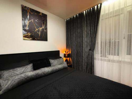 a bedroom with a black bed and a window at DOMINO apartamentai, SELF CHECK-IN in Panevėžys