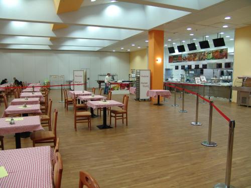 a restaurant with tables and chairs and a person in the kitchen at Hostel Kristal in Vinkovci