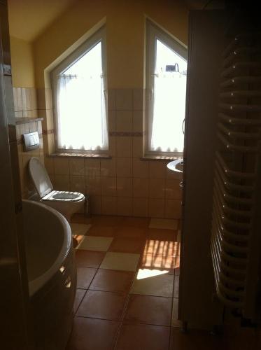 La salle de bains est pourvue de 2 lavabos, de toilettes et de 2 fenêtres. dans l'établissement Mieszkanie w Centrum Olesna, à Olesno