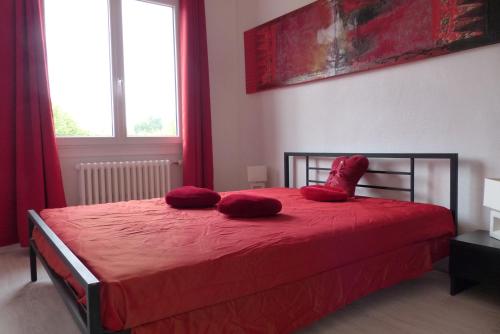 Un dormitorio con una cama roja con almohadas rojas. en Gîte Au fil de l'eau, en Muides-sur-Loire