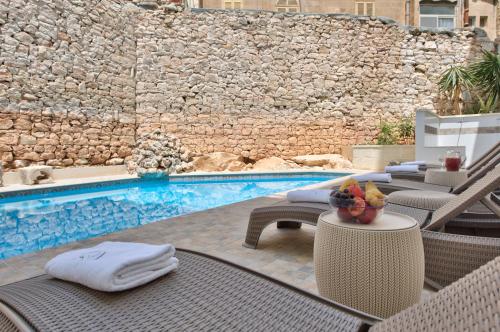 a pool with wicker chairs and a table with a table at Palazzo Violetta in Sliema