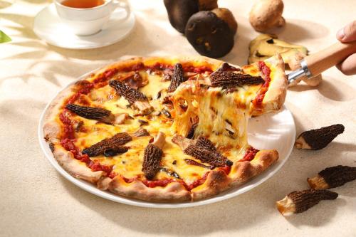 a pizza sitting on a plate on a table at Holiday Inn Fuzhou Exhibition Center in Fuzhou