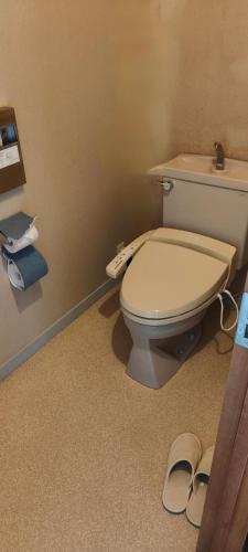 a bathroom with a toilet and a pair of slippers at 和みの宿いろり 甘露の湯付き in Shirahama