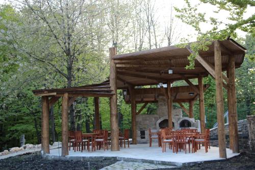 a wooden pavilion with tables and chairs and a fireplace at Cetatuia in Măgura