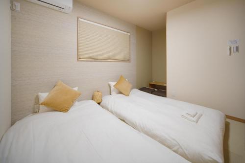 two beds in a room with white sheets and pillows at 静和 旅タイム岸里美楽 in Osaka