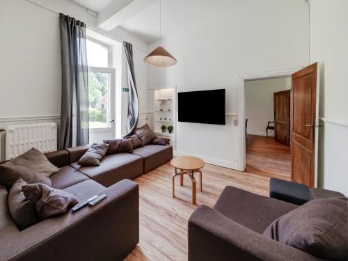 a living room with a couch and a tv at Castle in Ferrières with Pond Garden in Ferrières