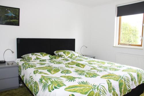 Schlafzimmer mit einem Bett mit einer grünen und weißen Bettdecke in der Unterkunft Gastenverblijf De Kapitein in Nieuwkoop