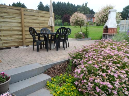 a patio with a table and chairs and flowers at Vakantiestudio Ciney in Chapois