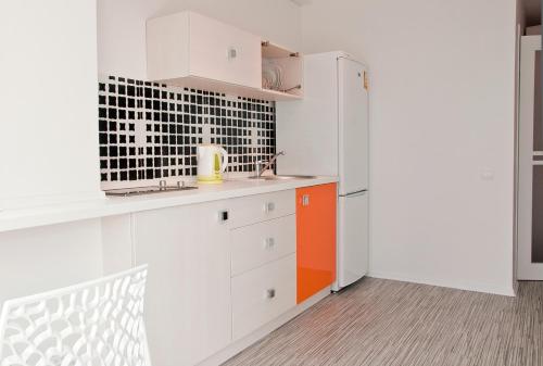 a kitchen with white cabinets and an orange and white refrigerator at Partner Guest House in Kyiv