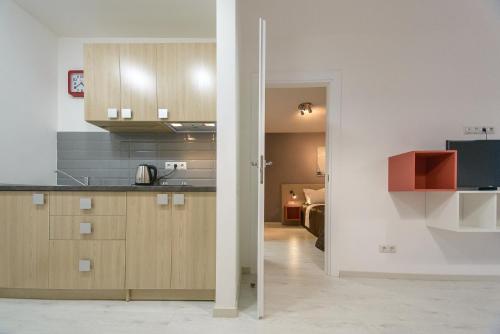 a kitchen with wooden cabinets and a living room at Partner Guest House in Kyiv