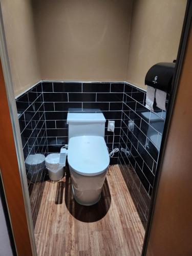 a bathroom with a toilet and black tiled walls at Central Plaza Hotel in Seryu-dong