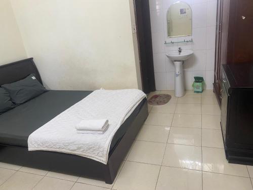 a small bedroom with a bed and a sink at Hottel ANH LONG in Buôn Ðũng