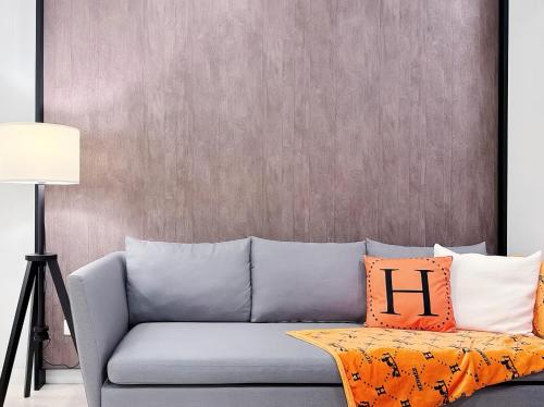 a gray couch with orange pillows in a living room at Tropicana The Residence KLCC in Kuala Lumpur