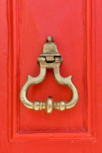 a red door with a brass door knocker on it at Palazzo Violetta in Sliema