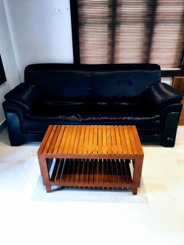 a black couch sitting in a living room with a coffee table at casamia garden in Batheri