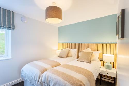 two beds in a white room with a window at North Devon Resort One bedroom sea view hot tub Residence in Ilfracombe