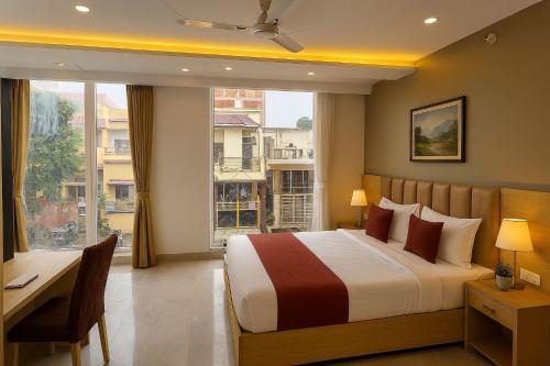 Un dormitorio con una cama y un escritorio y una ventana. en Perfectstayz Premium Kaashin near Kashi Ghat, en Varanasi