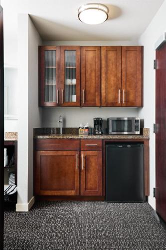 a kitchen with wooden cabinets and a black dishwasher at Hyatt House Seattle/Redmond in Redmond