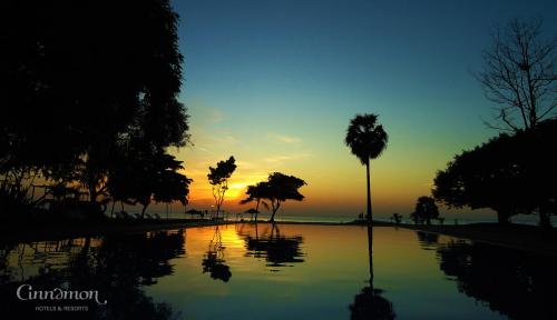 a sunset over a body of water with palm trees at Trinco Blu by Cinnamon in Trincomalee