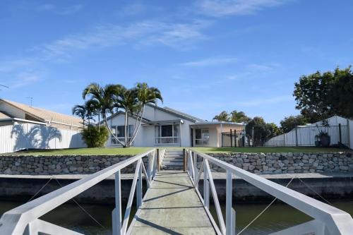 a bridge over the water in front of a house at Waterfront holiday home in Banksia Beach