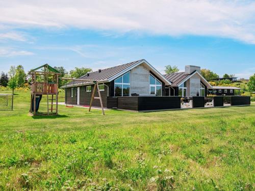 a house with a playground in a field at 20 person holiday home in Glesborg in Glesborg