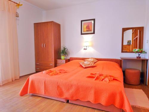 a bedroom with a bed with an orange blanket at Apartments Radis in Zaton