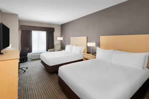 a hotel room with two beds and a flat screen tv at Stone Hill Norman, Trademark Collection by Wyndham in Norman