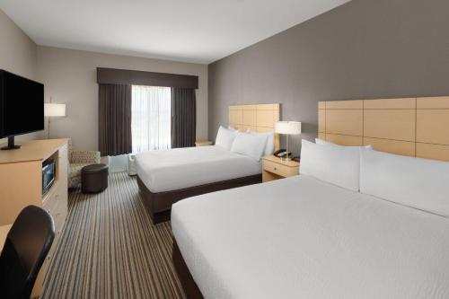 a hotel room with two beds and a flat screen tv at Stone Hill Norman, Trademark Collection by Wyndham in Norman