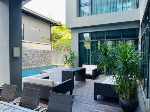a patio with tables and chairs and a pool at Lavanya H Villa 12A Luxury bungalow with private swimming pool H 豪华泳池别墅 in Pantai Cenang