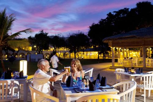 a man and woman sitting at a table with a drink at Trinco Blu by Cinnamon in Trincomalee